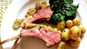 Herb Crusted Rack of Lamb with potatoes and broccoli on white plate