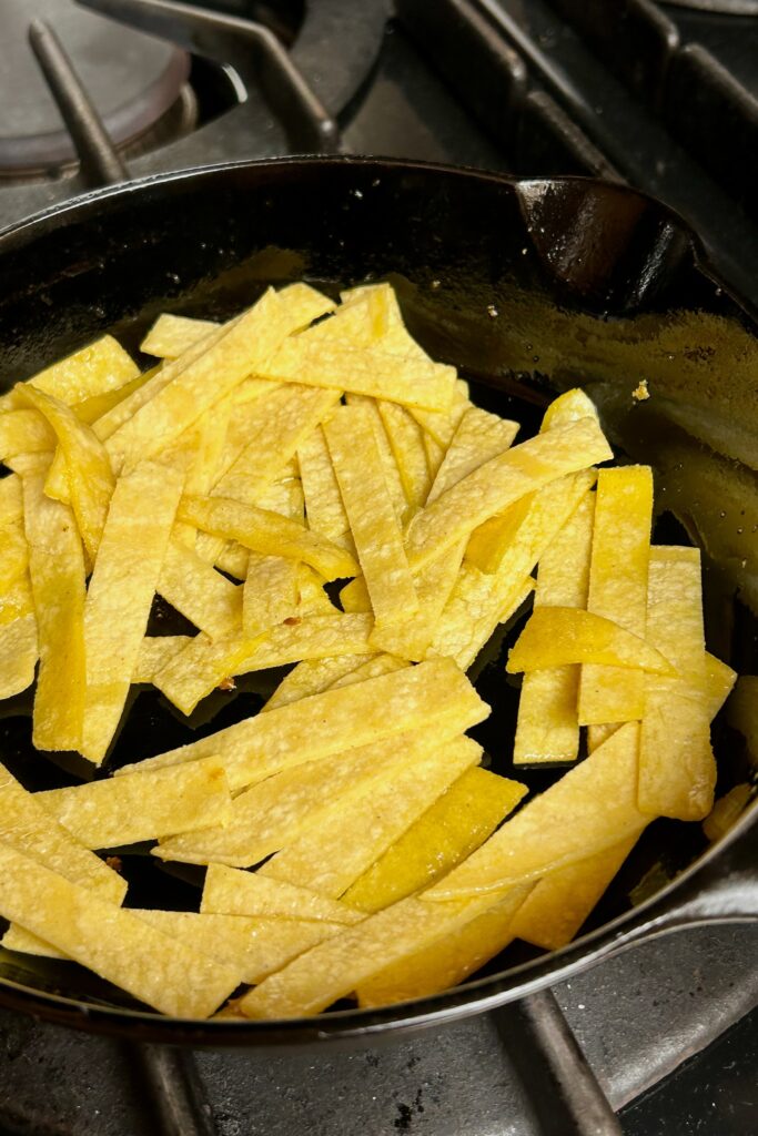 Tortilla cut into strips and gently tossed in lightly oiled black skillet. 