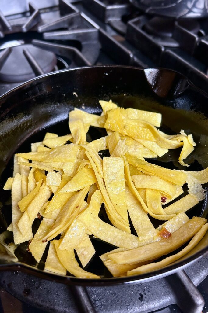 Tortilla cut into strips and gently tossed in lightly oiled black skillet. 